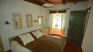 A bedroom with a bed, a dresser, a lamp, and a door.