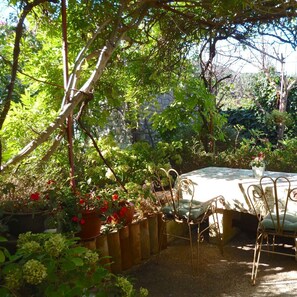 A garden patio with a table and chairs, surrounded by potted plants and trees. - Charming 2-Bedroom Apartment for 4 Guests (Veli Lošinj)