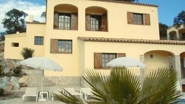 A two-story building with a yellow facade, multiple windows with shutters, and a stone staircase leading to the entrance. -  Luxury Air Conditioned Villa Close to Calonge Centre - Fantastic Views (Calonge)