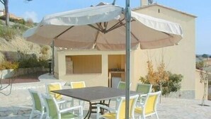 A patio with a table and chairs, an umbrella, and a building in the background. -  Luxury Air Conditioned Villa Close to Calonge Centre - Fantastic Views (Calonge)