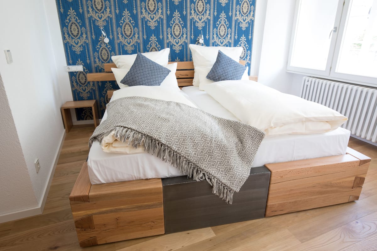 A bed with a wooden frame, white bedding, and patterned pillows.