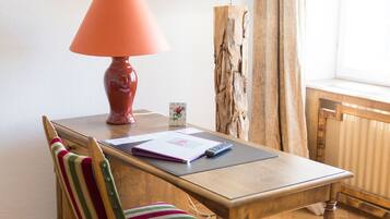 A wooden desk with a lamp, a chair, and a notebook.