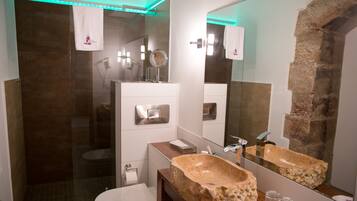 Une salle de bain moderne avec un grand miroir, un lavabo en pierre et une douche à parois de verre.