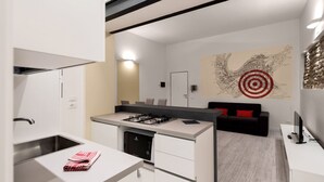 Una cocina moderna con lavavajillas integrado, estufa a gas y un lavamanos. Hay una zona de comedor con un sofá negro y un cojín rojo. Una gran obra de arte abstracta adorna la pared.