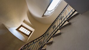 Una escalera en espiral con barandilla de hierro forjado y un pequeño ventanal en la parte superior.