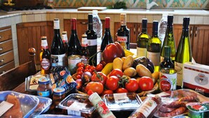A kitchen counter with various food items and bottles of wine.