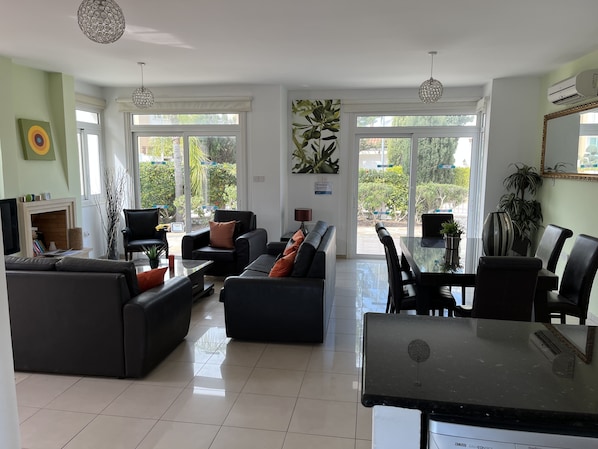 A modern living room with a sofa, chairs, a dining table, and a TV.