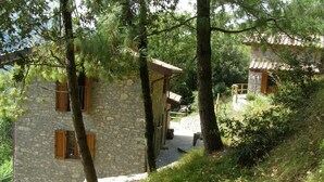 Un edificio de piedra con contraventanas de madera, una escalera de piedra y una terraza de madera.