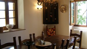 Un comedor con una mesa de madera, sillas, una araña y una ventana con vistas a zonas verdes.