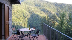 Un balcón con una mesa y sillas, con vistas a una montaña boscosa.