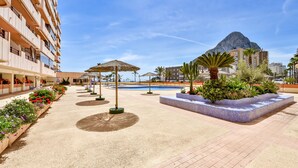 A hotel courtyard with a pool, outdoor seating, and a mountain view. - Zafiro 18B - Front line apartment with sea views and direct access to the beach (Calpe / Calp)
