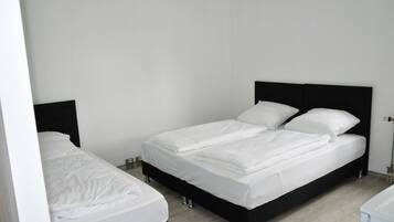 A clean, modern bedroom with a black headboard bed, white bedding, and a small bedside table.