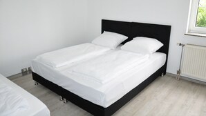 A double bed with a black headboard in a room with white walls and a window. - Hotel Vladi (Walldorf)