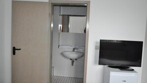 A bathroom with a sink, mirror, and a television on a stand. - Hotel Vladi (Walldorf)