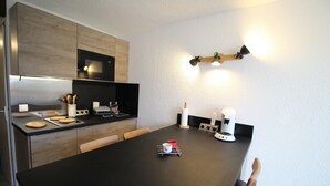 A modern kitchen with a black countertop, wooden cabinets, and a built-in microwave. - LES 2 ALPES .. RENTED APARTMENT WITHOUT OPPOSITE (Mont-de-Lans)