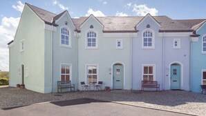 A multi-story building with a symmetrical facade, featuring a central entrance with a door and windows on each floor. - Portballintrae 10 Ballaghmore Cottages  (Bushmills)