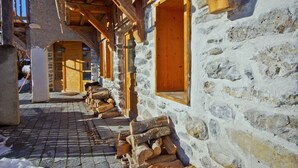 A rustic stone building with wooden beams and open windows. - Chalet 3 Valleys France (Saint-Jean-De-Belleville)