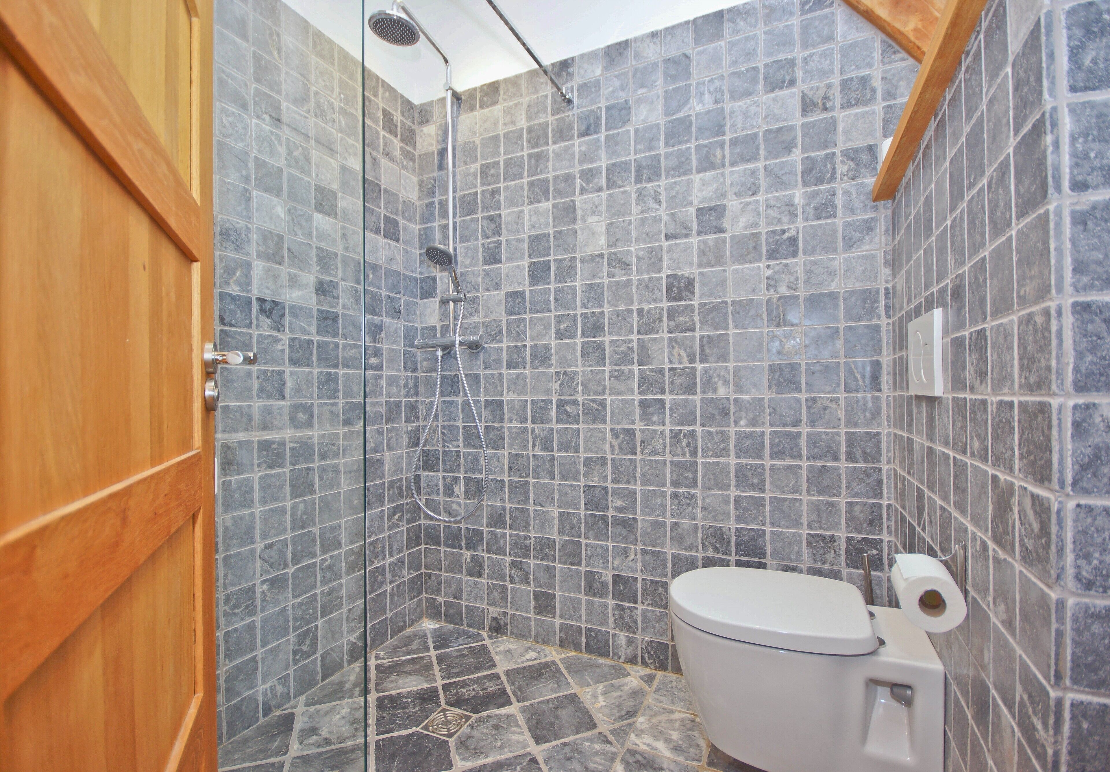 A bathroom with a shower, toilet, and tiled walls.