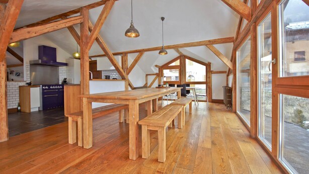 A spacious kitchen with wooden beams, a long wooden table, and benches. - Chalet 3 Valleys France (Saint-Jean-De-Belleville)