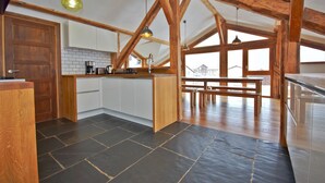 A kitchen with wooden beams, a central island, and a view of a building outside. - Chalet 3 Valleys France (Saint-Jean-De-Belleville)