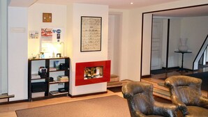 Un salon avec une cheminée, une bibliothèque et des fauteuils en cuir.