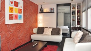Un salon moderne avec un canapé blanc, un tapis rouge et un mur orné d’un motif géométrique.