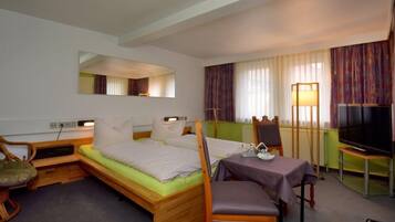 A hotel room with a bed, a desk, a chair, a television, and a mirror.