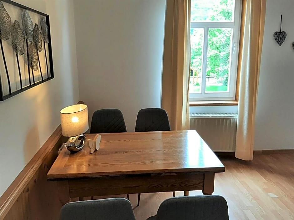 Un comedor con una mesa y sillas de madera, una lámpara y una ventana con cortinas.