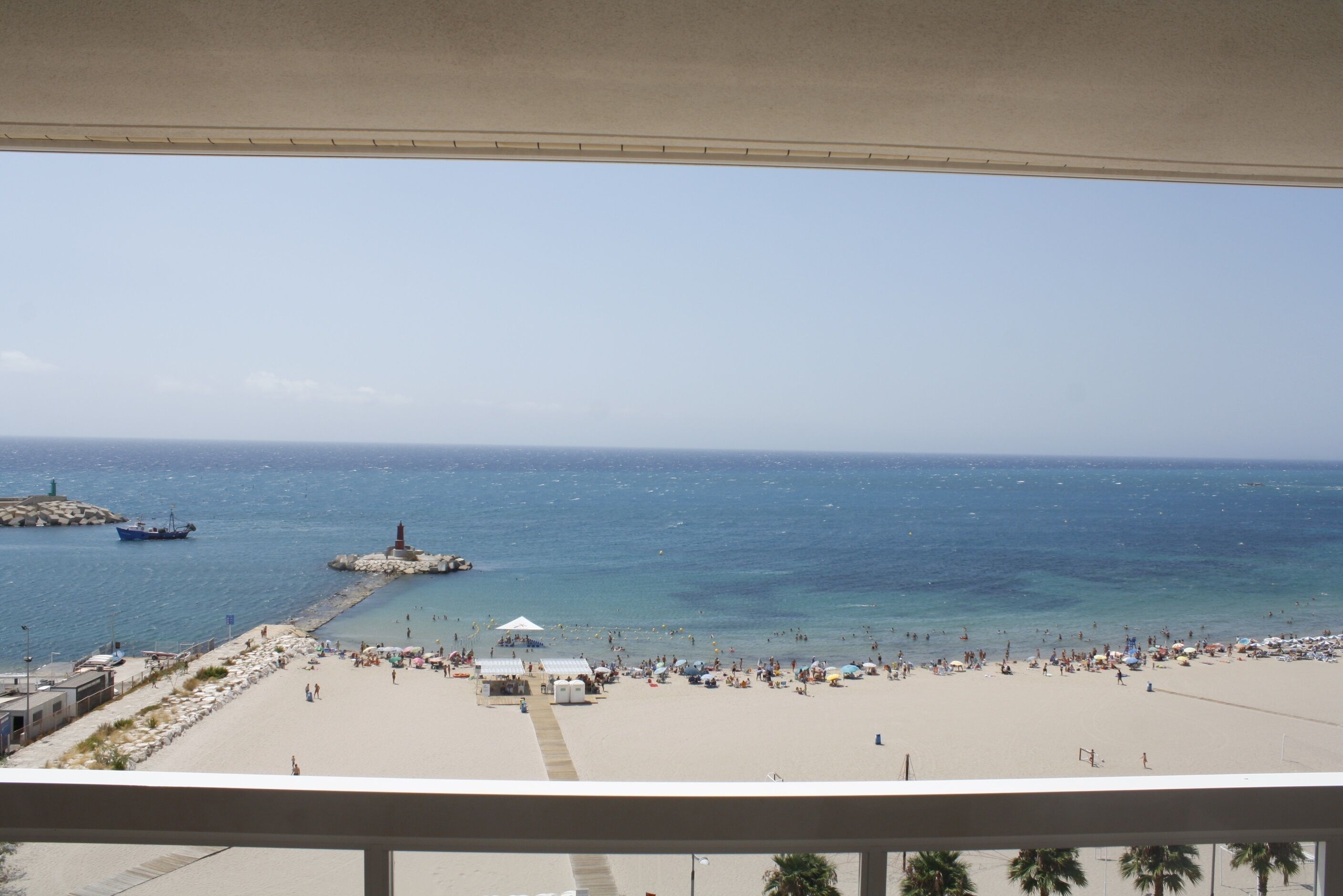 A beach with a pier and a lighthouse, and a view of the ocean.