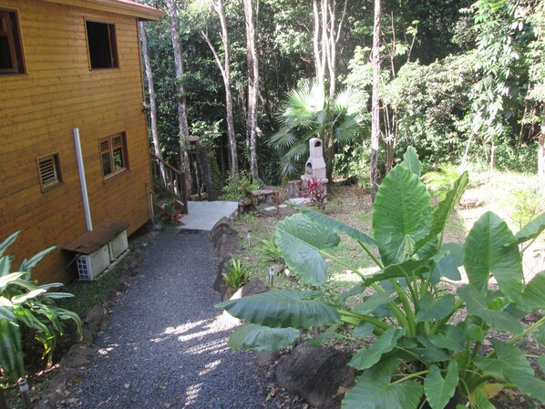 Un bâtiment en bois avec un chemin de gravier menant à une terrasse en bois.