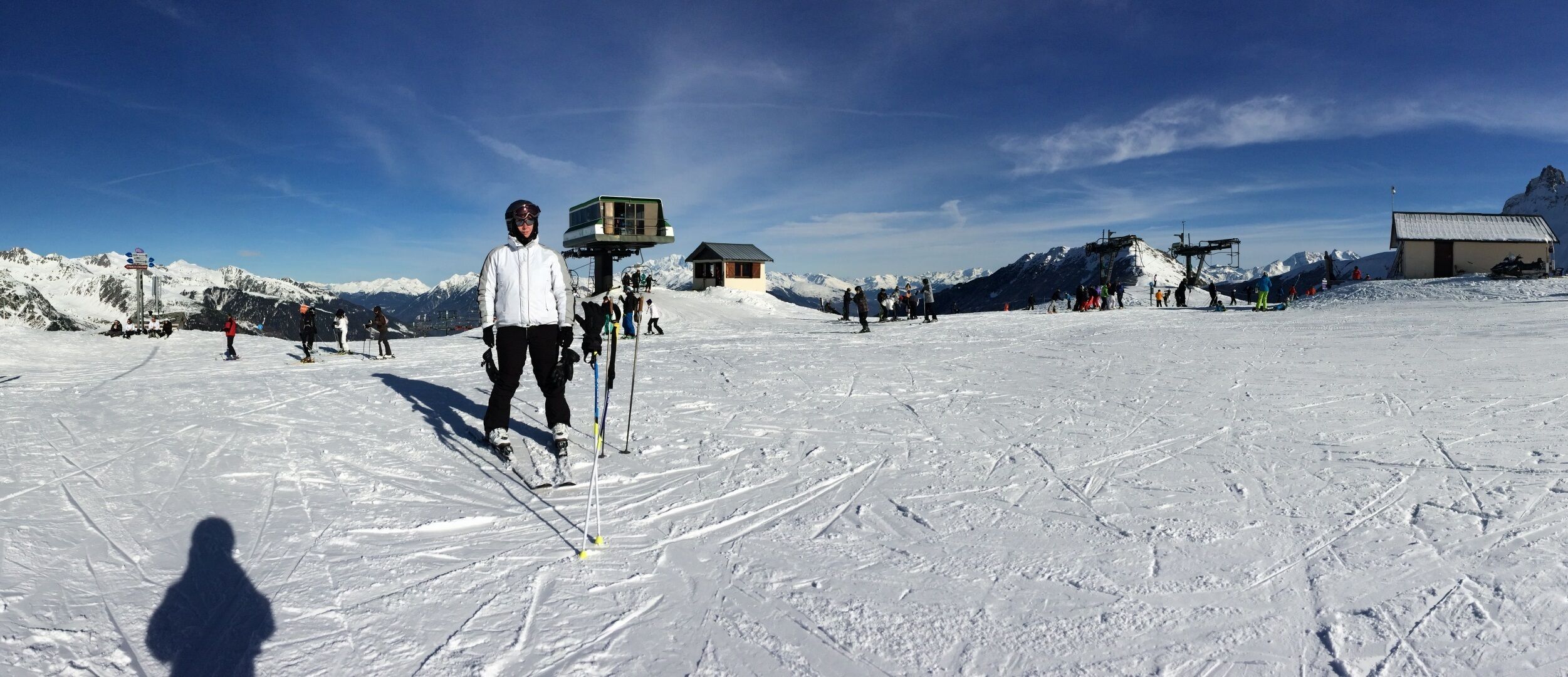 Eine Skipiste mit Skifahrern, einer Seilbahn und einem Berg im Hintergrund.