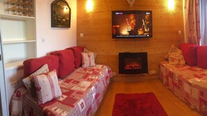 Un salon chaleureux avec deux canapés, une cheminée et un téléviseur fixé au mur.