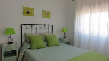 A bedroom with a bed, two nightstands, two lamps, and two wall art pieces.