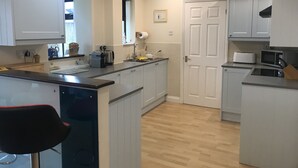 Una cocina moderna con armarios blancos, una encimera de madera, un ventilador de techo y un microondas.