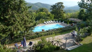 A pool area with lounge chairs and a view of mountains.