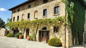 A stone building with a rustic facade, multiple windows, and a covered entrance area with potted plants.