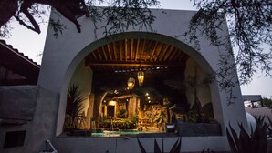 Um edifício com entrada em arco, piscina e lanternas penduradas.