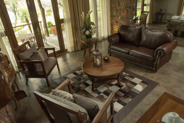 A spacious living room with a leather sofa, wooden chairs, a coffee table, and a checkered rug. - Hotel Casa Legado Spa & Resort (Aguascalientes)
