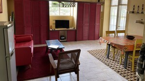 A compact living space with a sofa, a small table, a TV, and a dining area with a table and chairs. - Apartment/ flat - Petit-bourg (PETIT BOURG)
