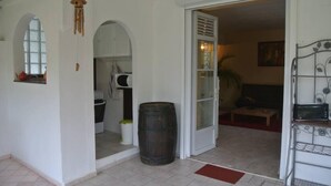A living room with a sofa, a coffee table, and a TV. There is a kitchen area with a stove and a sink. A large barrel is visible in the center of the room. - Apartment/ flat - Petit-bourg (PETIT BOURG)