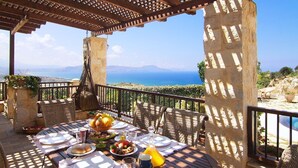 Ein Tisch, gedeckt für eine Mahlzeit, mit Blick auf Meer und Berge.