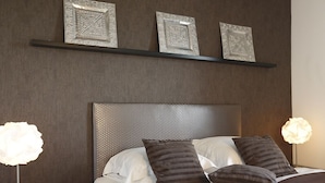 A neatly made bed with a textured headboard, two bedside lamps, and three decorative wall pieces above it. - Nature & Chateaux à Villandry (Artannes-sur-Indre)