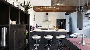 A modern kitchen with a central island, bar stools, and a dining table. - Nature & Chateaux à Villandry (Artannes-sur-Indre)