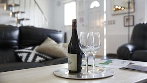 A bottle of wine and two glasses on a tray in a living room with a black leather couch and a staircase in the background. - Nature & Chateaux à Villandry (Artannes-sur-Indre)