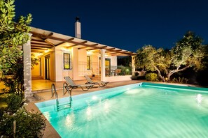 Ein modernes Haus mit Pool, Sitzgelegenheiten im Freien und einer überdachten Terrasse.