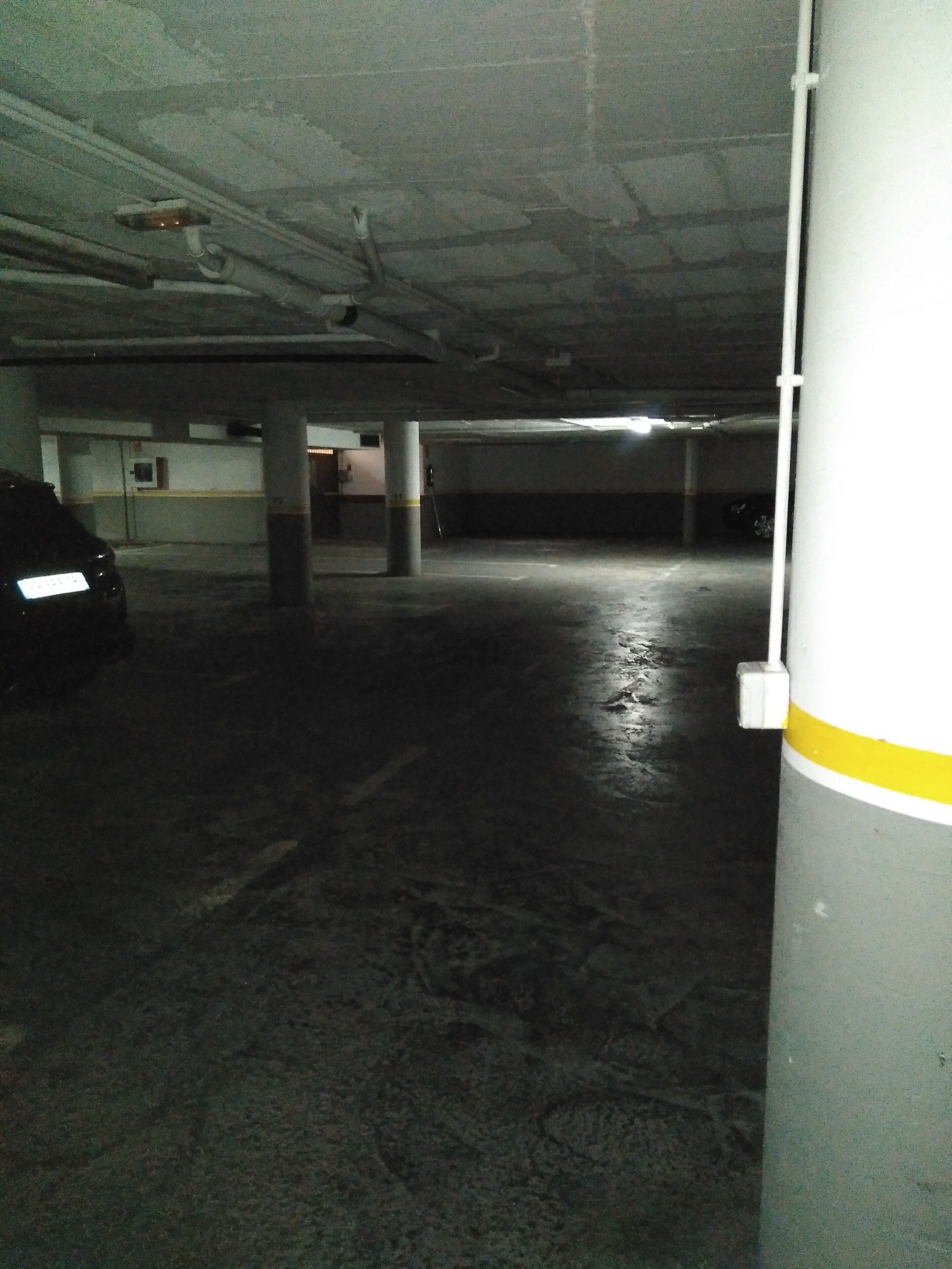 An underground parking garage with concrete pillars and a wet floor.