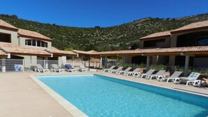 A swimming pool with lounge chairs and a mountainous backdrop.