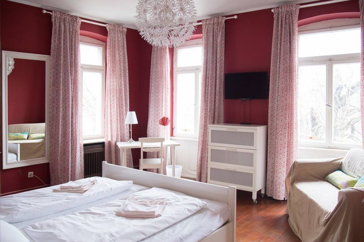 A room with two beds, a desk, a chair, a TV, and a dresser.