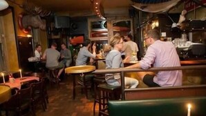 A restaurant interior with wooden tables and chairs, a green booth, and a mounted animal head on the wall. - Hemingway's Hostel Heidelberg (Heidelberg)