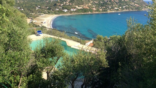 Une vue sur la côte, avec une piscine, une plage et des bâtiments situés sur une colline.